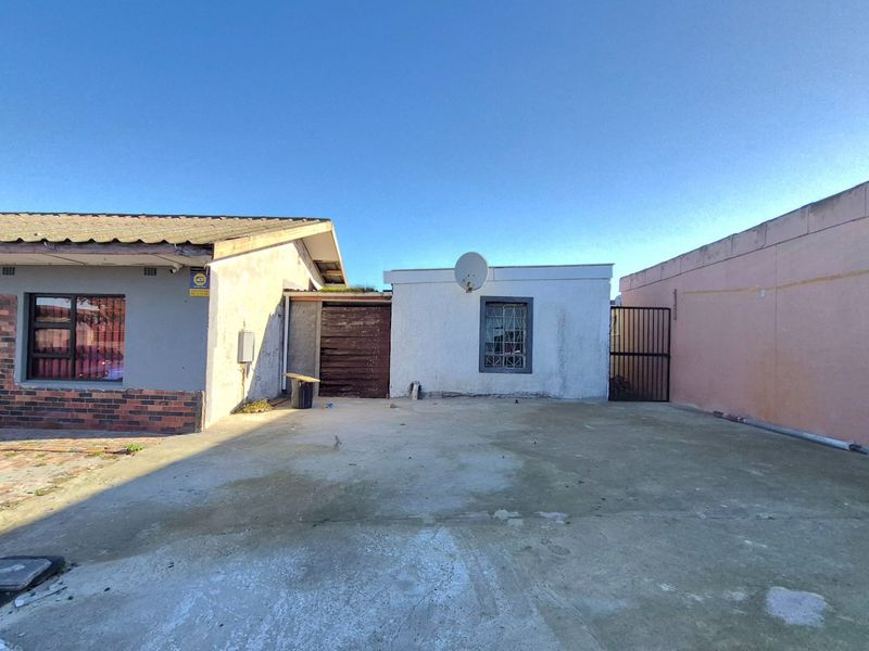 Rear exterior view of the property featuring a concrete driveway, security gate, and brick and rendered wall finishes.