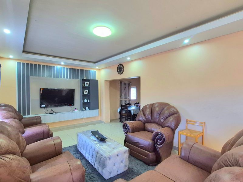 Spacious living room featuring a built-in media unit, recessed ceiling with downlights, and neutral tiled flooring, offering a comfortable and functional living space.