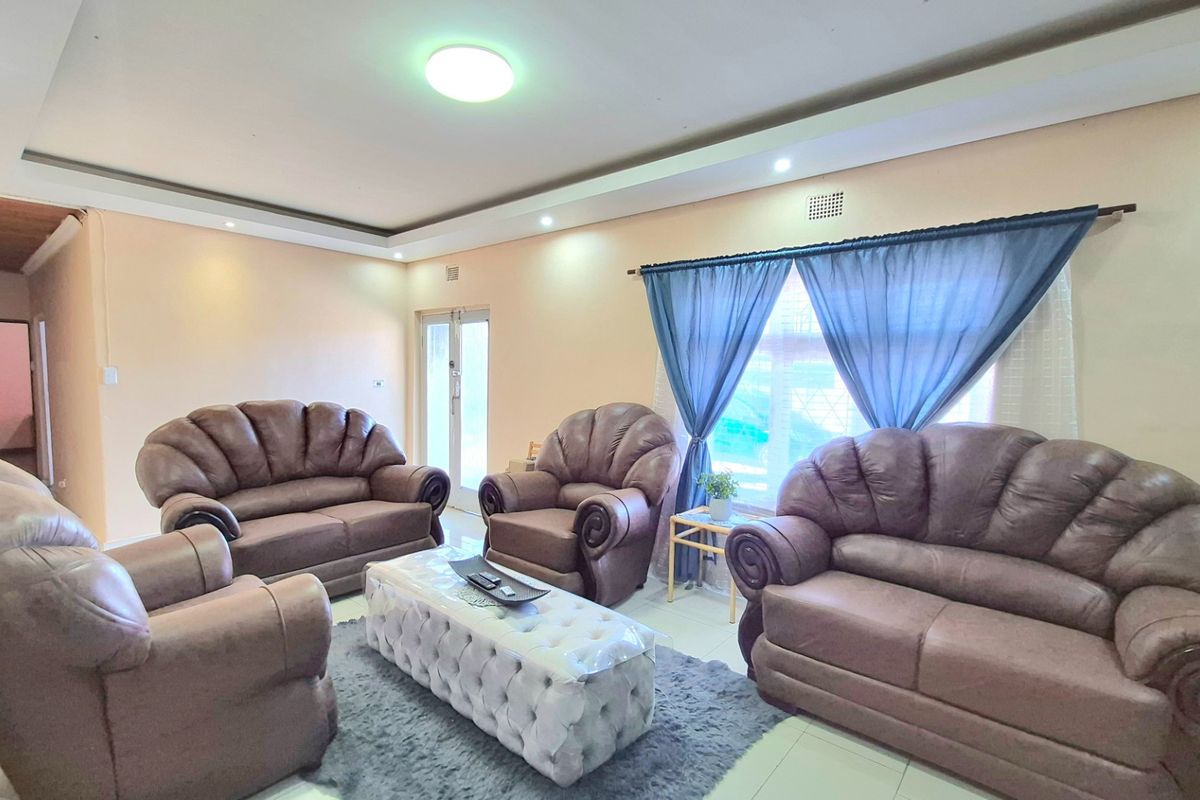 A spacious living room featuring tiled flooring, recessed ceiling lighting, and large windows with natural light.