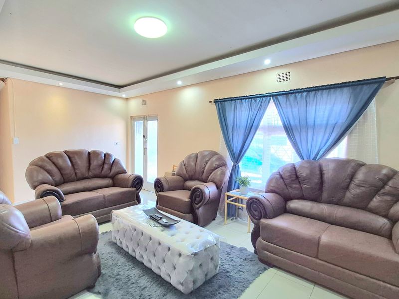 A spacious living room featuring tiled flooring, recessed ceiling lighting, and large windows with natural light.