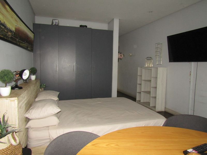 A bedroom featuring dark grey built-in cupboards and recessed ceiling lighting, providing a functional and neutral sleeping space.