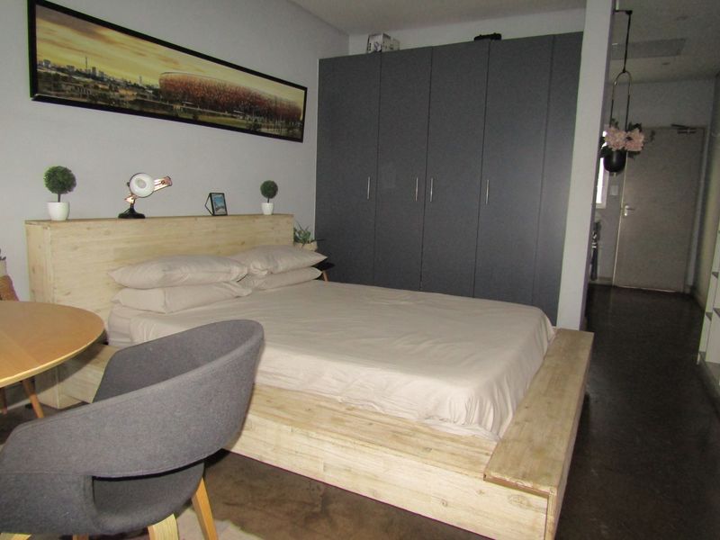 A bedroom featuring dark grey built-in cupboards and a modern wooden platform bed frame.