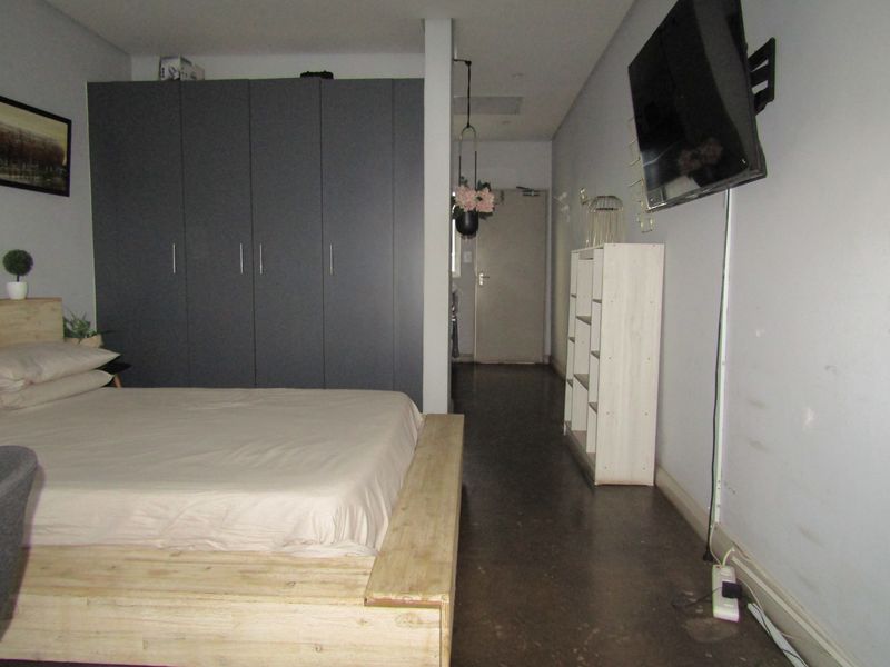 Bedroom featuring built-in cupboards and concrete flooring, offering a functional layout with potential for cosmetic updates to enhance the space.