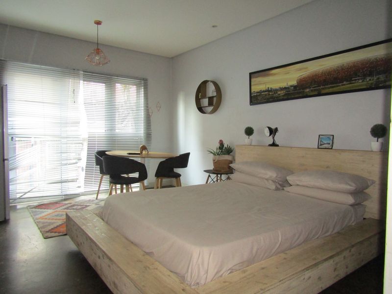 A bedroom featuring a sliding glass door with venetian blinds and a pendant light fixture.