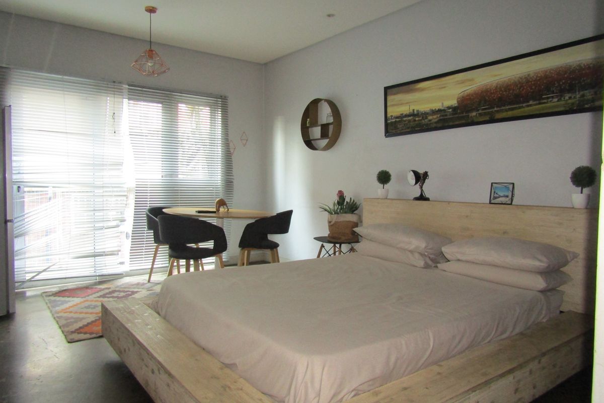 A bedroom featuring a sliding glass door with venetian blinds and a pendant light fixture.