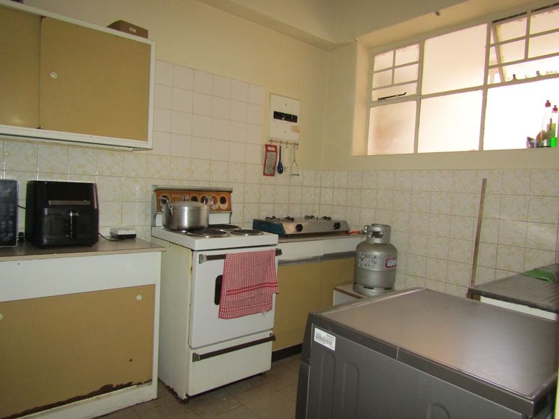 A dated kitchen featuring original cabinetry, tiled splashbacks, and a freestanding stove, offering significant potential for modernization and renovation.
