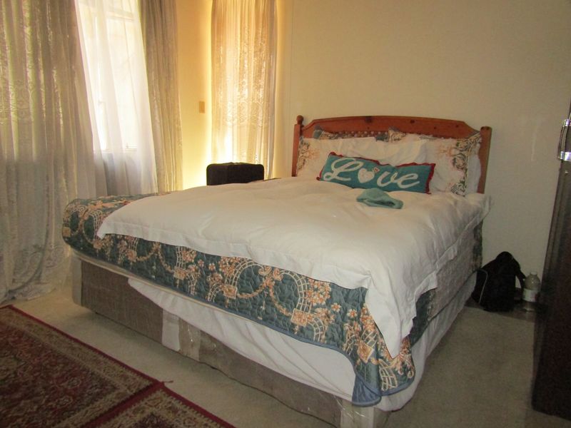 A standard bedroom featuring carpeted flooring and natural light from the window.