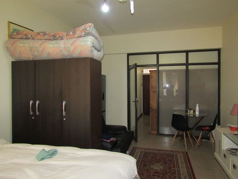 A bedroom featuring tiled flooring and a glass partition wall with a hinged door leading to an adjacent space.