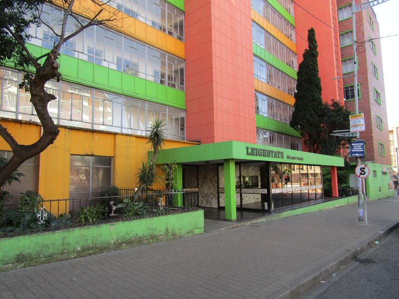 Exterior view of the Leighstate apartment building featuring a covered entrance, multi-colored facade, and enclosed balcony windows along the street front.