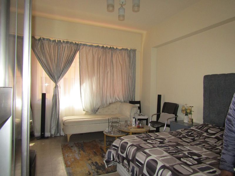 A bedroom featuring tiled flooring and a central ceiling light fixture, providing a functional living space.