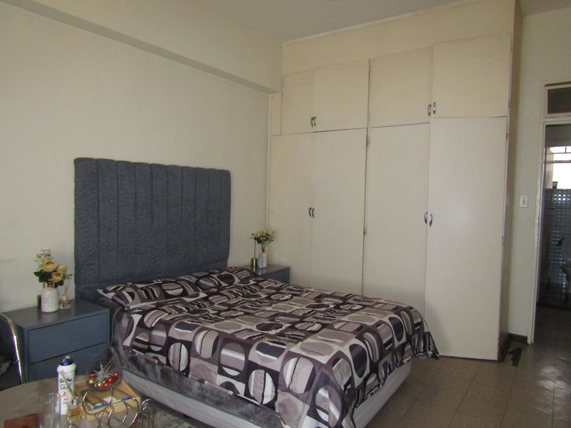 A bedroom featuring built-in floor-to-ceiling cupboards and tiled flooring, offering functional storage space in a standard apartment layout.