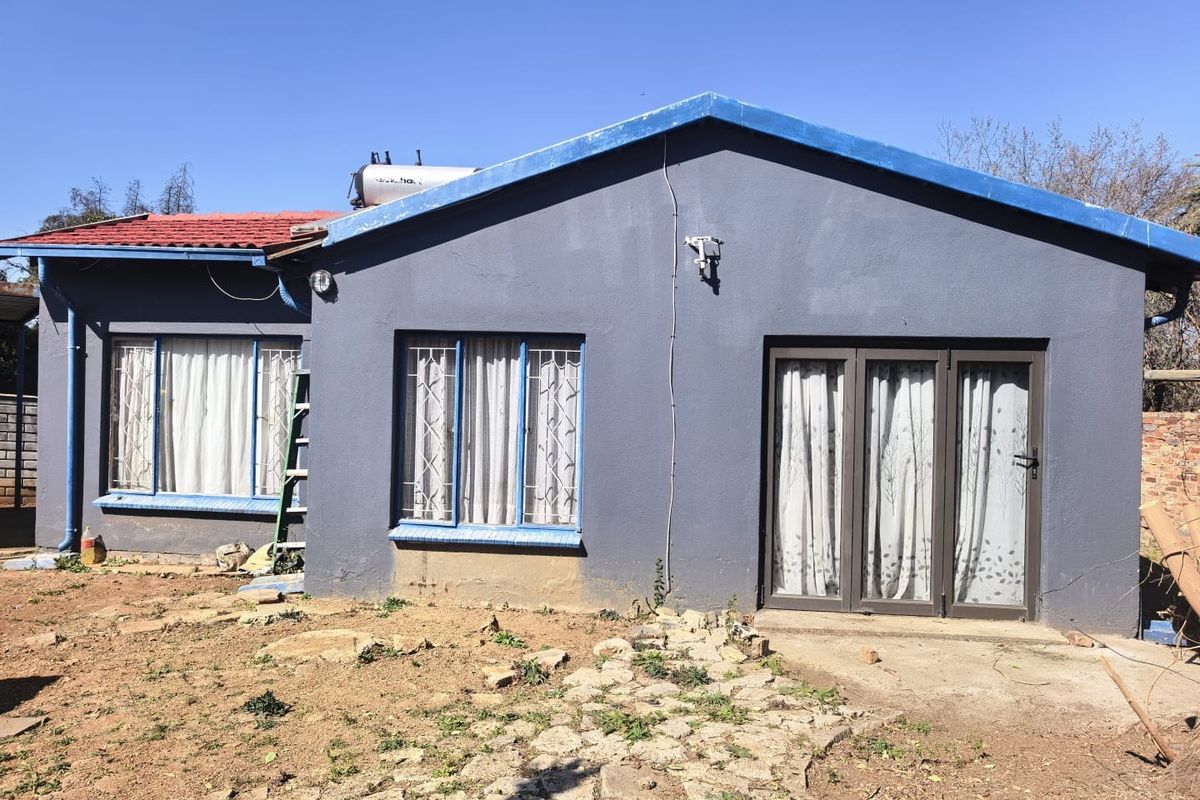 Rear exterior view of the house featuring a solar water heater, metal roofing, and sliding glass door access to the garden area.