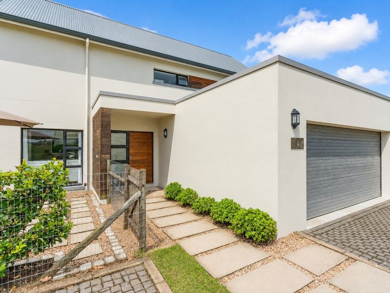 Modern front facade featuring a paved walkway, timber entrance door, and integrated single garage with a clean, contemporary architectural design.