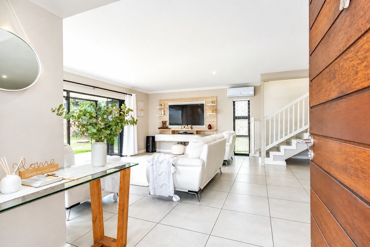 Bright and modern open-plan living area featuring tiled floors, a built-in media unit, split-system air conditioning, and direct access to the outdoor space.
