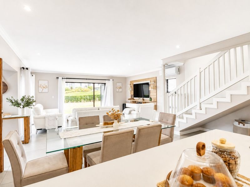 Bright open-plan living and dining area featuring tiled floors, a modern staircase with balustrade, and sliding glass doors leading to the exterior.
