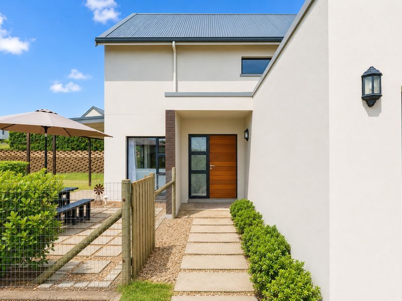 Modern front entrance featuring a timber door, paved walkway, and clean architectural lines with well-maintained exterior finishes.