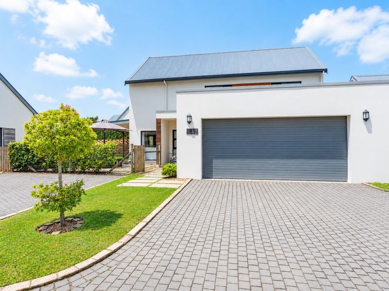 Modern front elevation featuring a paved driveway, a double garage with a sectional door, and a well-maintained garden area.