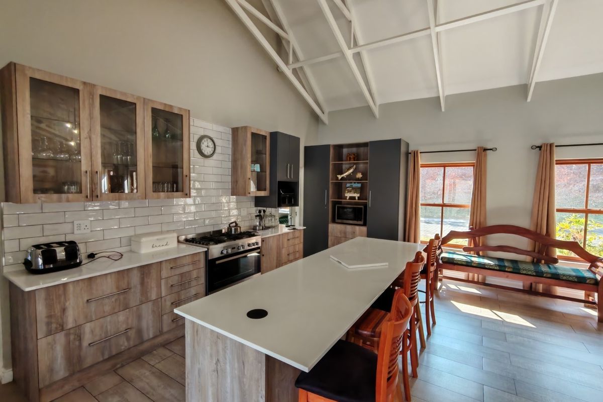 Modern kitchen featuring a large island, quartz countertops, subway tile backsplash, and a striking vaulted ceiling with exposed white rafters.