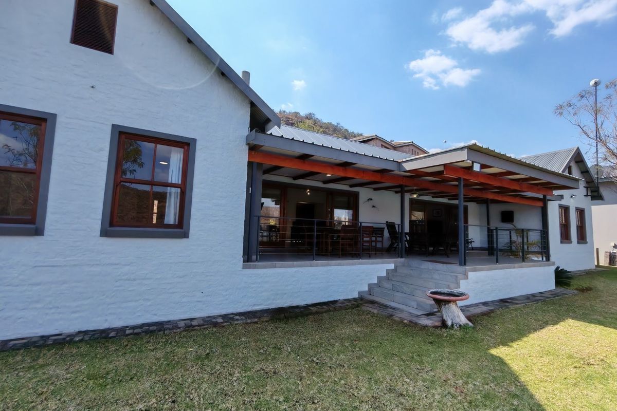 Rear view of the house featuring a spacious covered patio with a timber pergola, concrete steps, and large sliding glass doors leading inside.