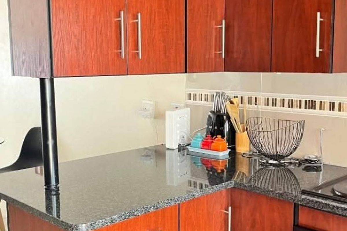 Compact kitchen featuring dark wood-look cabinetry, granite countertops, a built-in oven, and a decorative tiled backsplash.
