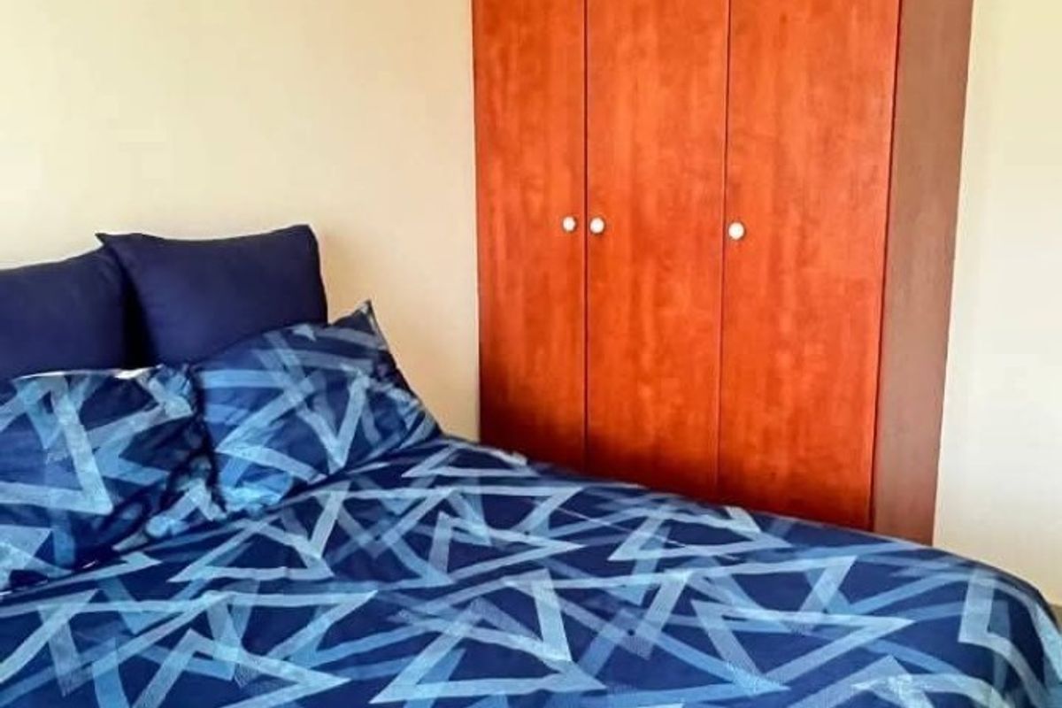 A bedroom featuring a built-in wooden wardrobe and tiled flooring.