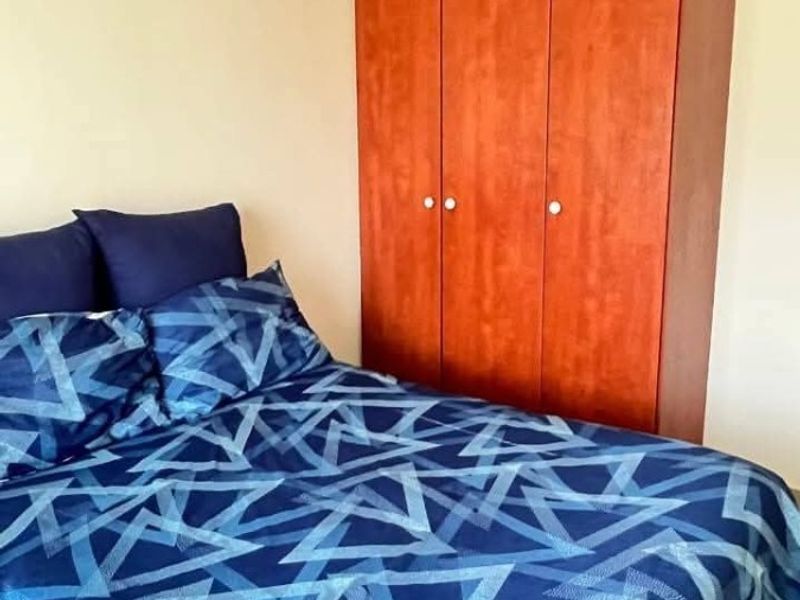 A bedroom featuring a built-in wooden wardrobe and tiled flooring.
