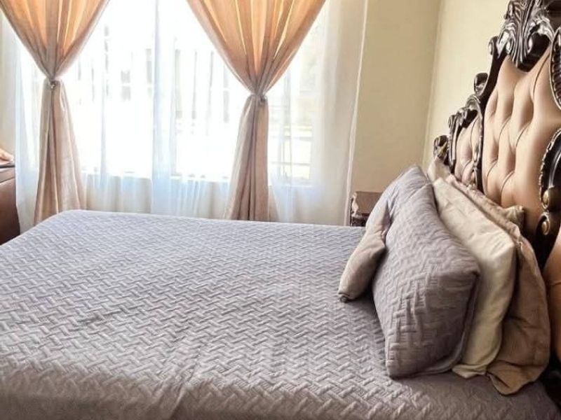 A bedroom featuring tiled flooring and a window with curtains, providing a functional and comfortable sleeping space.