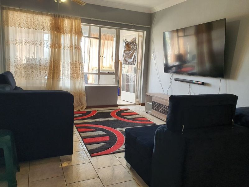 A comfortable living room featuring tiled flooring, a ceiling fan, and direct access to an enclosed balcony through a sliding glass door.