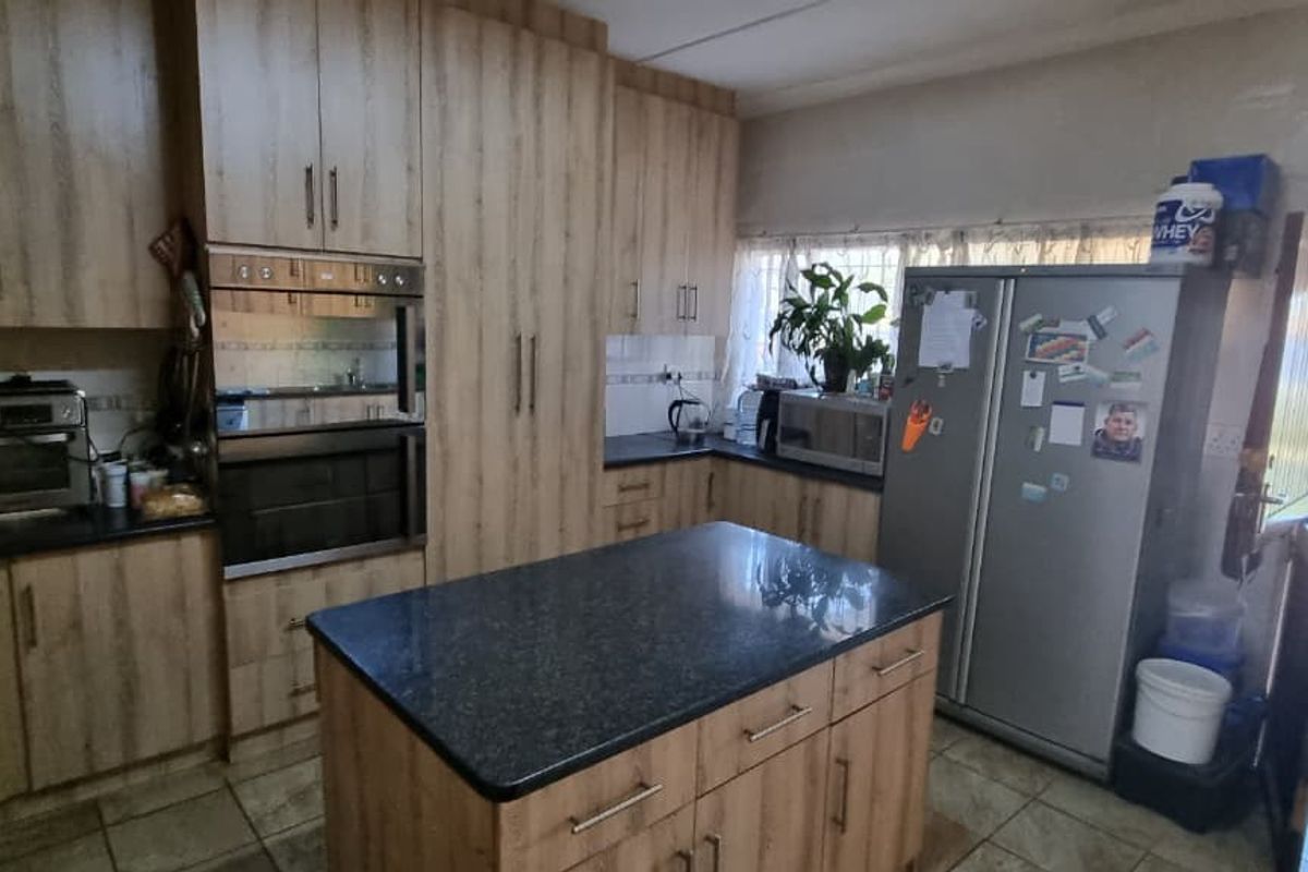 A functional kitchen featuring wood-finish cabinetry, a central island with stone countertops, built-in oven and microwave, and direct access to the outdoor area.