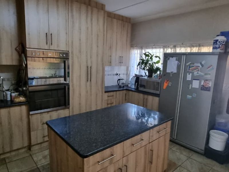 A functional kitchen featuring wood-finish cabinetry, a central island with stone countertops, built-in oven and microwave, and direct access to the outdoor area.