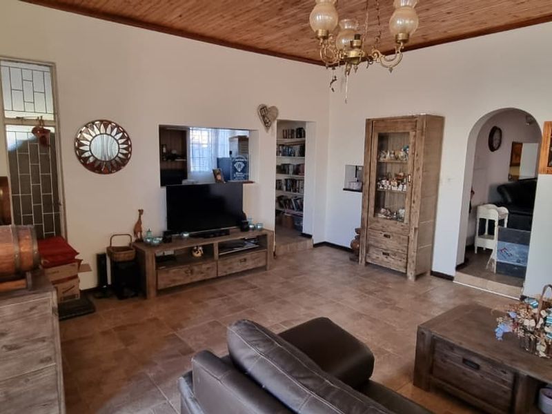 Spacious living room featuring a timber ceiling, tiled flooring, and an arched entryway leading to adjacent living spaces.