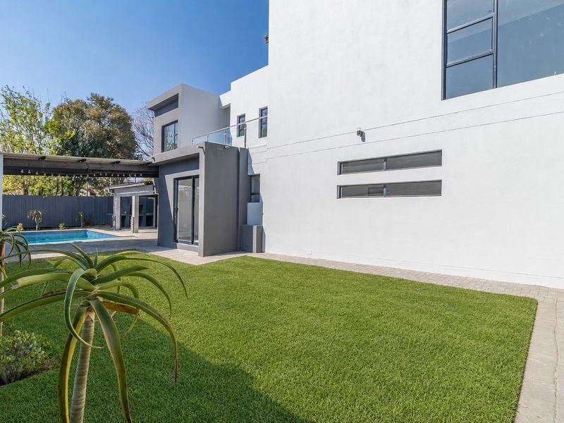 Rear view of a modern two-story home featuring a swimming pool, covered patio area, and well-maintained lawn with paved pathways.