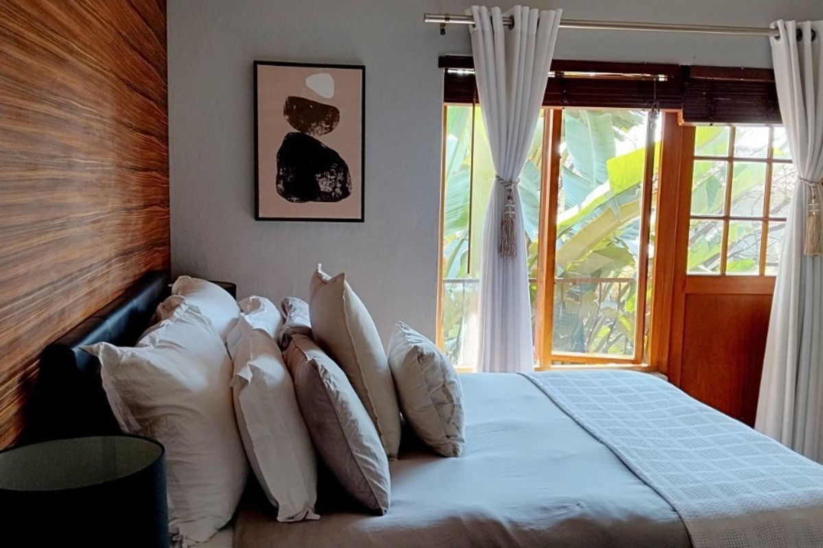 A well-maintained bedroom featuring a decorative wood-paneled accent wall, a ceiling fan, and direct access to an outdoor area through a timber-framed door.