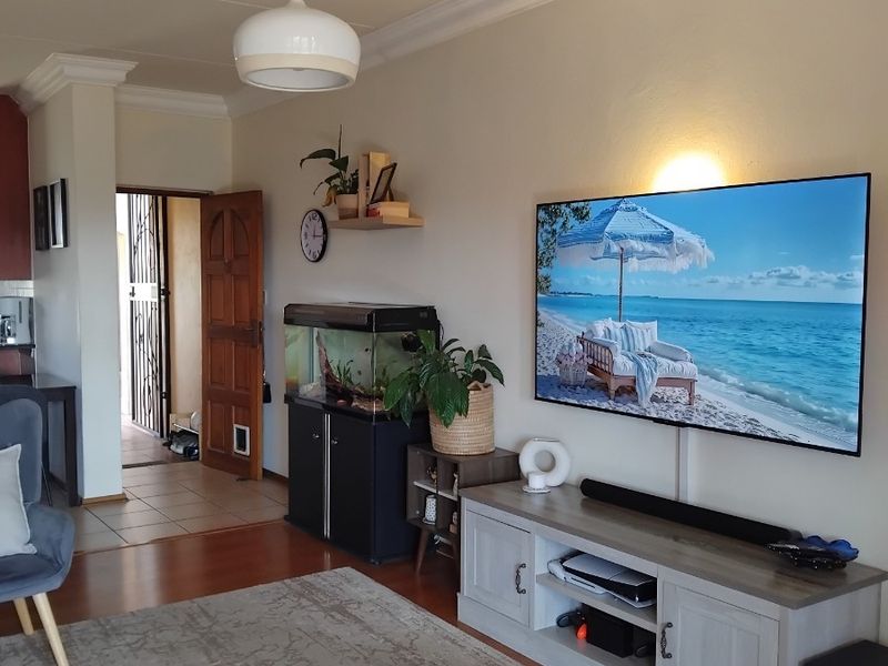 A comfortable living room featuring laminate flooring, decorative coving, and a neutral wall finish, providing a functional and inviting space.