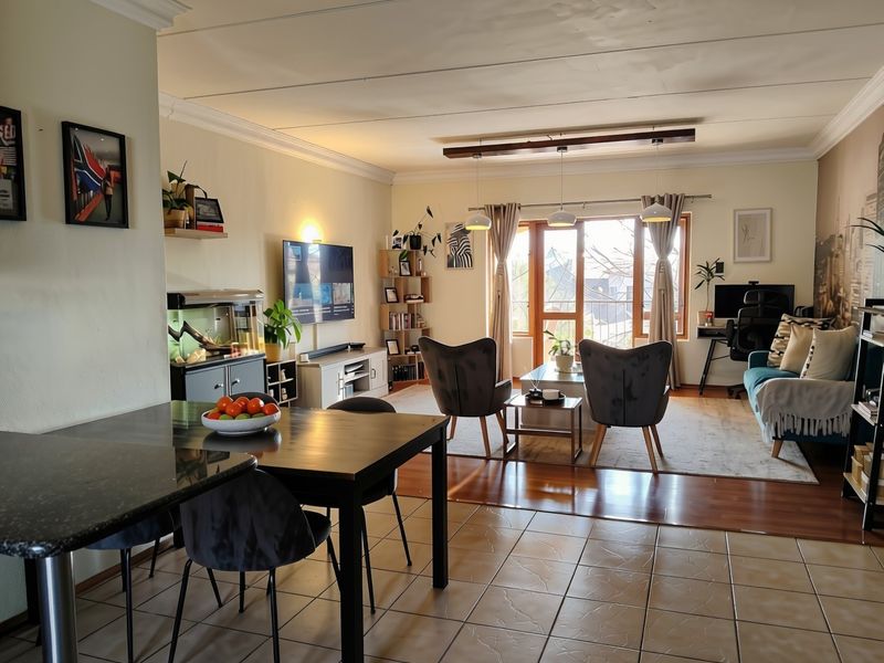 Spacious open-plan living and dining area featuring a mix of tiled and laminate flooring, pendant lighting, and access to a balcony through sliding doors.