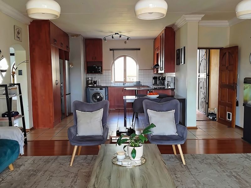 Open-plan living and kitchen area featuring a mix of tiled and laminate flooring, built-in cabinetry, and an arched window providing natural light.