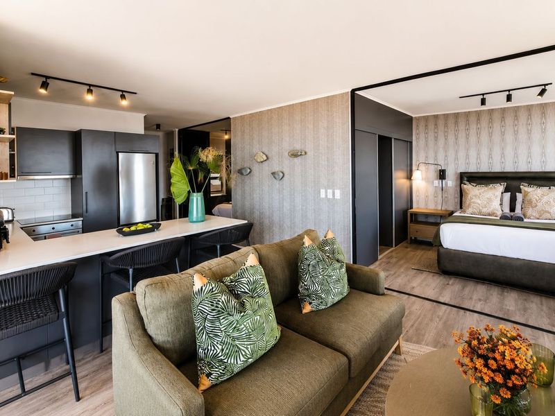Modern open-plan apartment featuring a sleek kitchen with island, integrated appliances, and a seamless transition into the bedroom area with sliding door access.