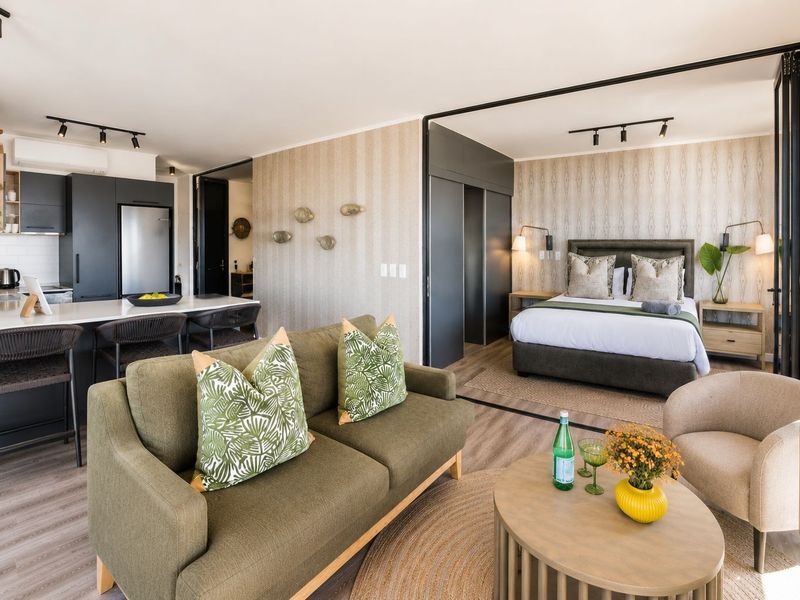 Modern open-plan apartment featuring a sleek kitchen with stone countertops, integrated living area, and a bedroom separated by a stylish black-framed glass partition.