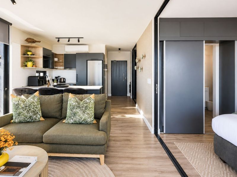 Modern open-plan apartment featuring a sleek kitchen, living area, and a bedroom partitioned by a sliding glass door with high-quality finishes throughout.
