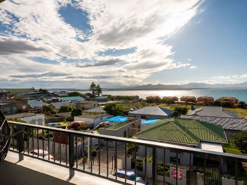 Elevated coastal view overlooking the surrounding residential neighborhood, coastline, and distant mountains from a balcony.