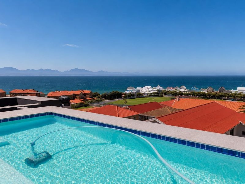 An elevated swimming pool featuring a clear view of the ocean, coastline, and surrounding residential neighborhood.