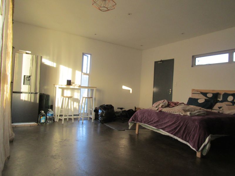Spacious bedroom featuring polished concrete floors, recessed lighting, and a mix of vertical and clerestory windows providing natural light.