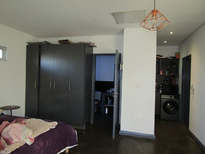 Bedroom featuring built-in wardrobes, concrete flooring, and an integrated en-suite bathroom with an adjacent laundry nook.