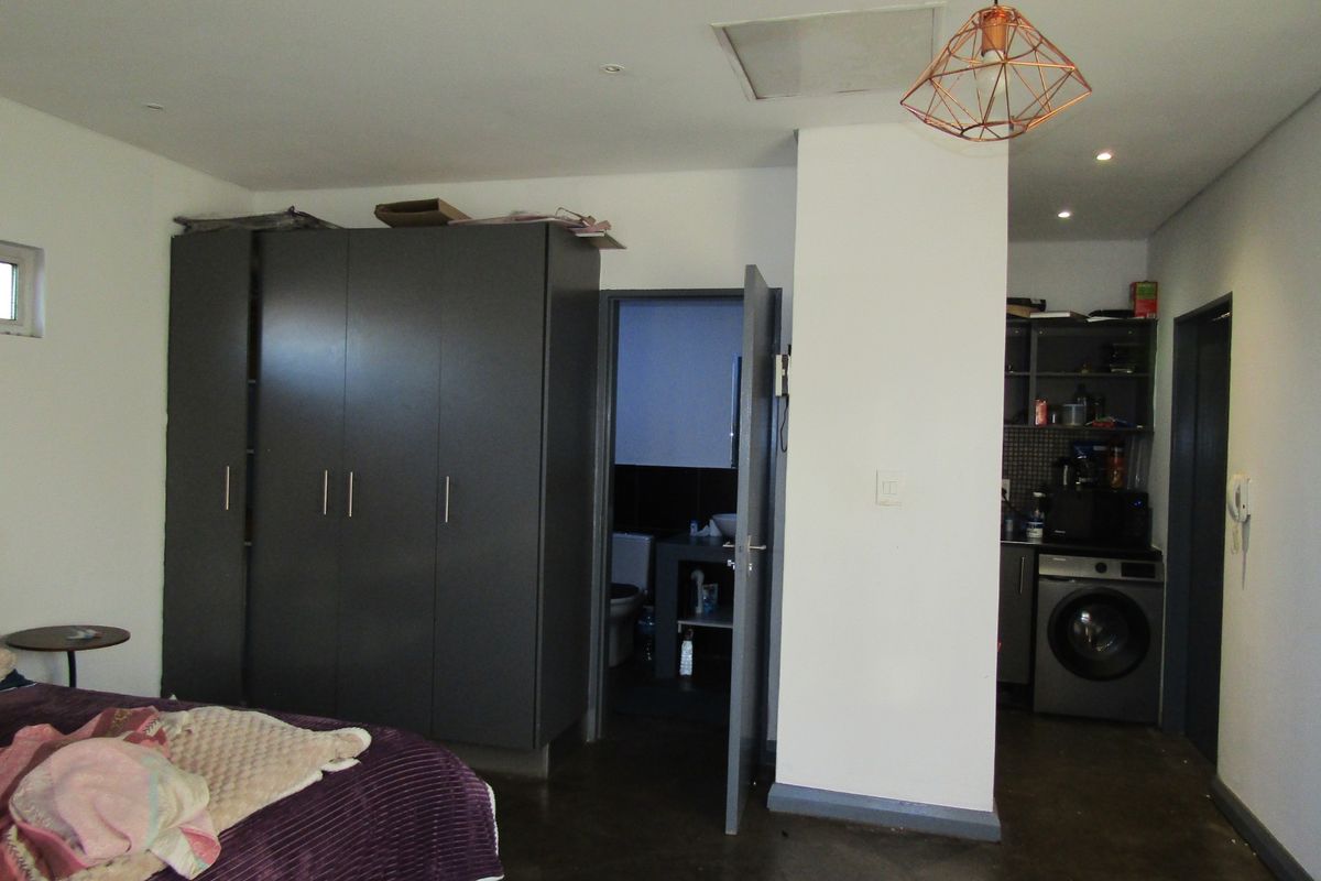 Bedroom featuring built-in wardrobes, concrete flooring, and an integrated en-suite bathroom with an adjacent laundry nook.