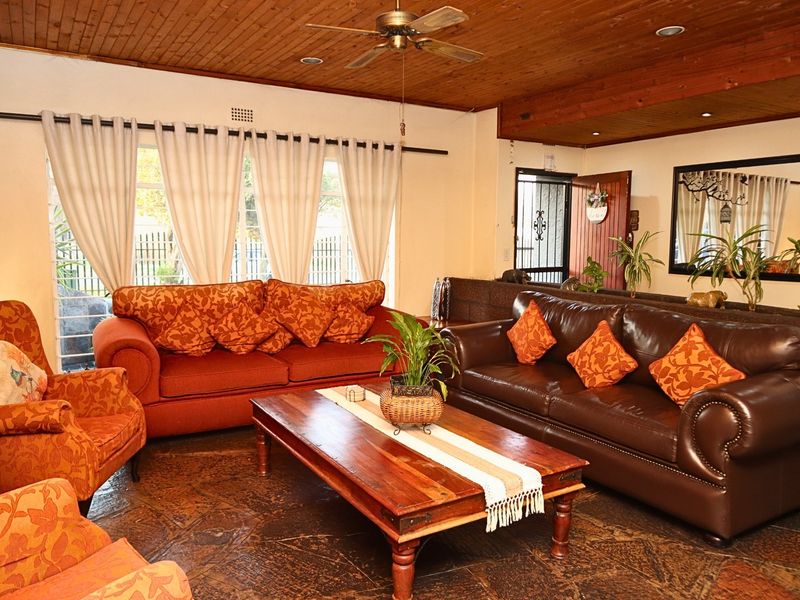 Spacious living room featuring a warm timber ceiling, ceiling fan, and durable stone flooring, creating a cozy and inviting atmosphere.