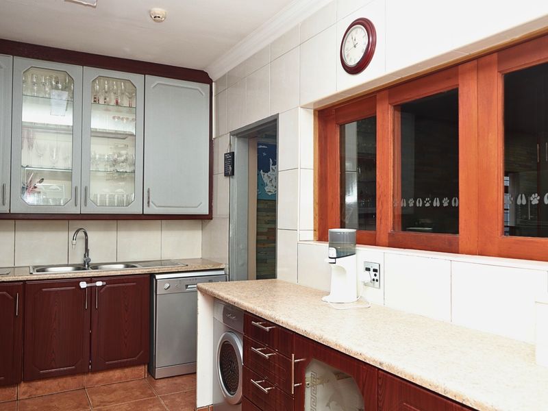 A functional kitchen featuring tiled splashbacks, laminate countertops, and a mix of dark wood and light-toned cabinetry with integrated sink and appliance space.