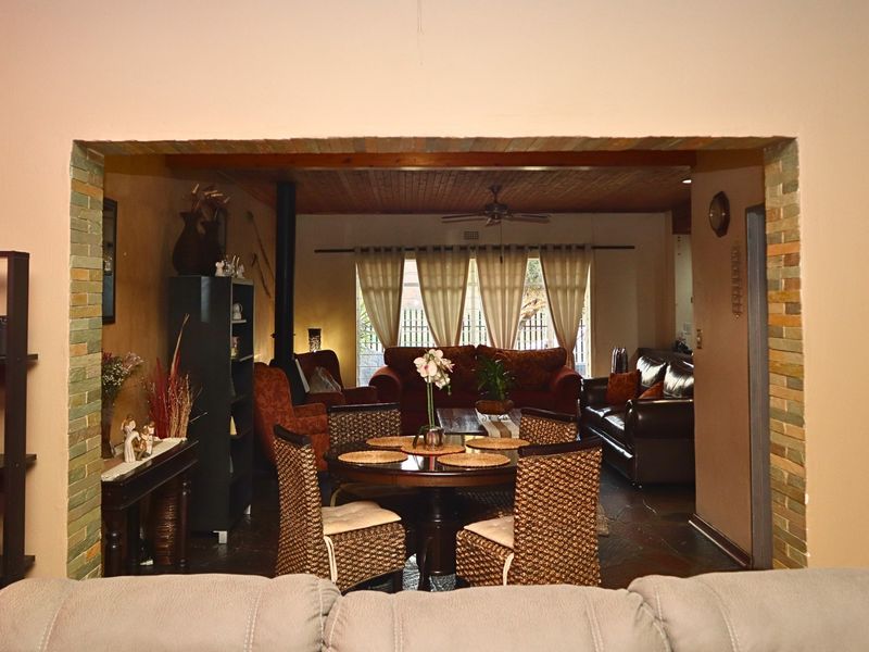 Open plan living and dining area featuring slate flooring, a timber ceiling, and a characterful exposed brick archway connecting the spaces.