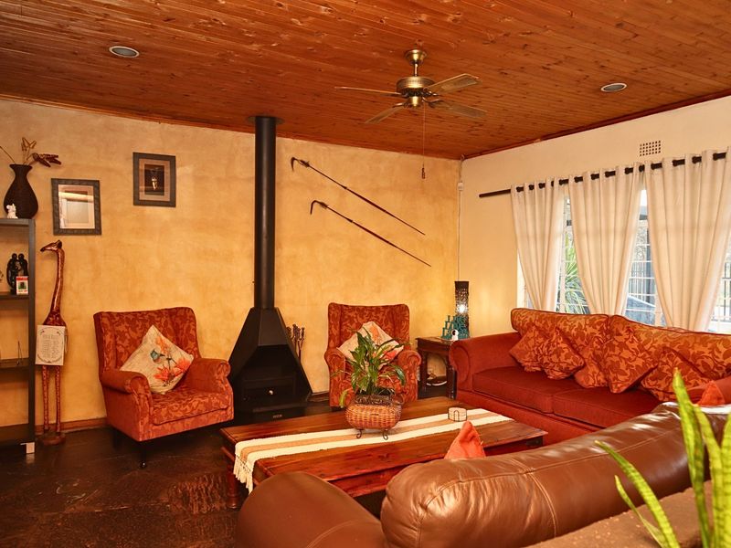 A cozy living room featuring a wood-paneled ceiling, stone flooring, and a prominent freestanding fireplace, creating a warm and rustic atmosphere.