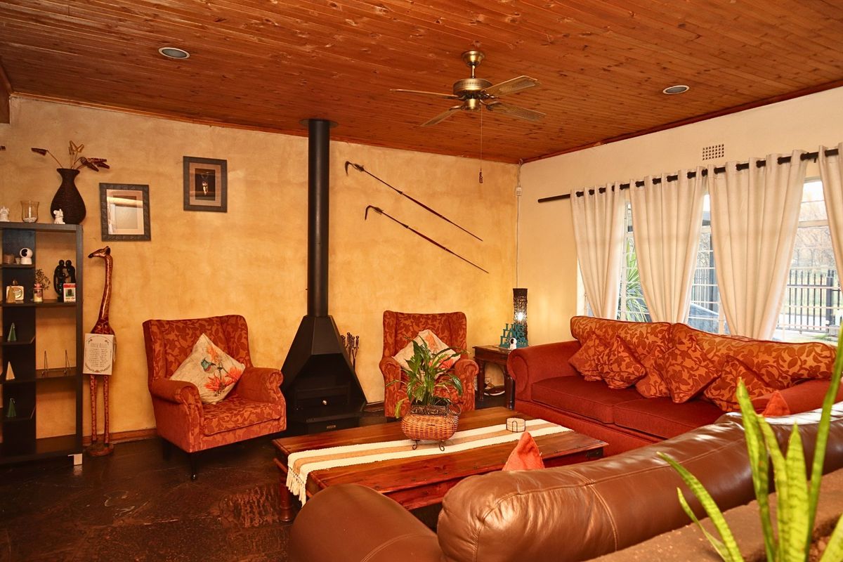 A cozy living room featuring a wood-paneled ceiling, stone flooring, and a prominent freestanding fireplace, creating a warm and rustic atmosphere.