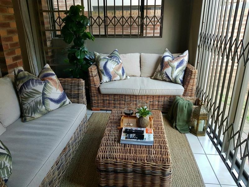 A covered patio area featuring tiled flooring, brick wall accents, and secure metal security gates, providing a protected outdoor living space.